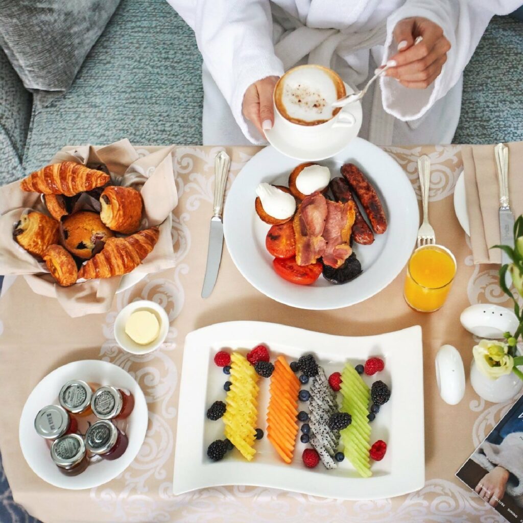 Table of food with a drink being held over by a person in a white suit