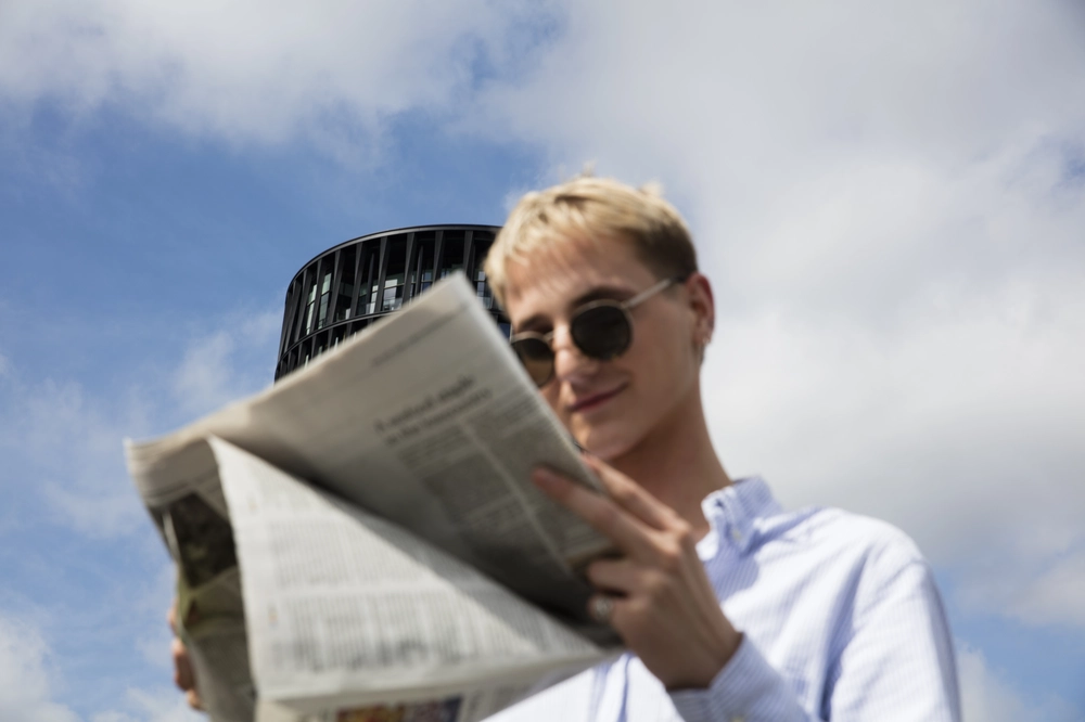 team member reading a newspaper outside