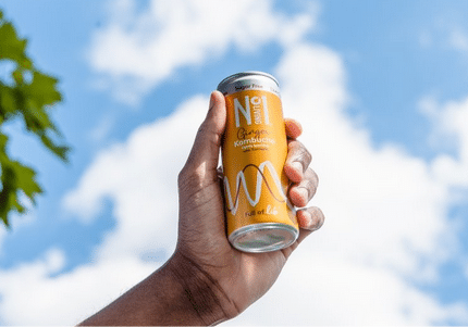 man holding a can of drink outwith with a blue sky