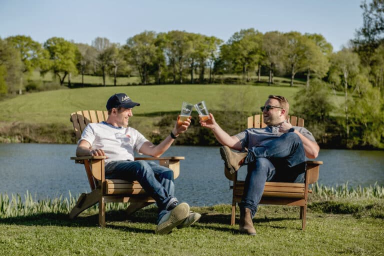 2 people with drinks by a lake